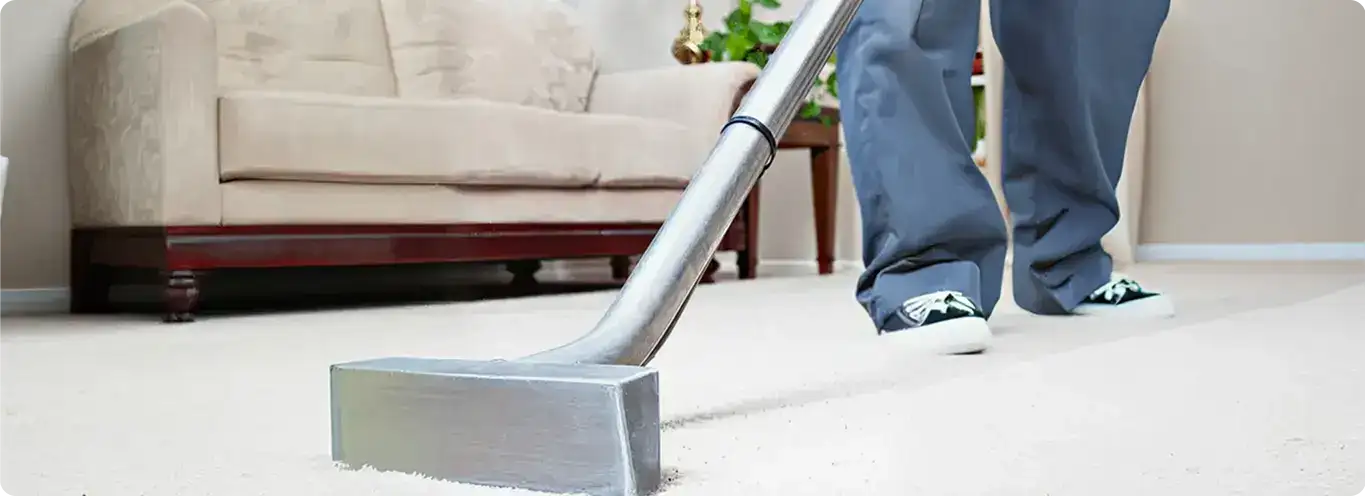 Carpet cleaning technician using a hot-water extraction wand on a light-colored carpet in a living room, Lakeland, FL.