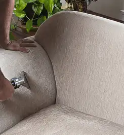 Professional upholstery cleaner deep-cleaning a fabric sofa with a handheld extraction tool and hose Lakeland, FL.